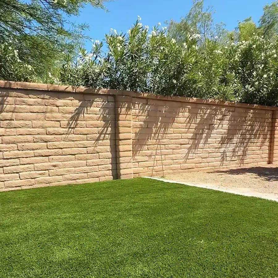 Close-up of a finished split-face CMU retaining wall holding a turf lawn
