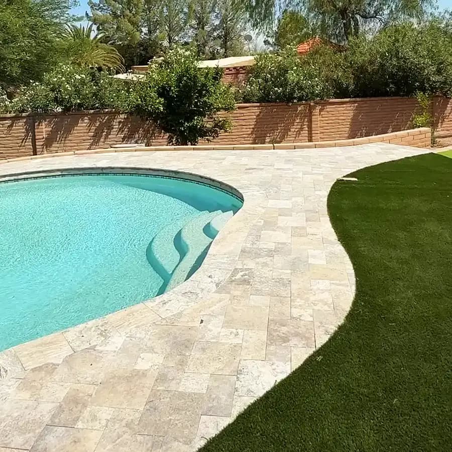 Close-up of travertine pool coping curving around a Tucson pool