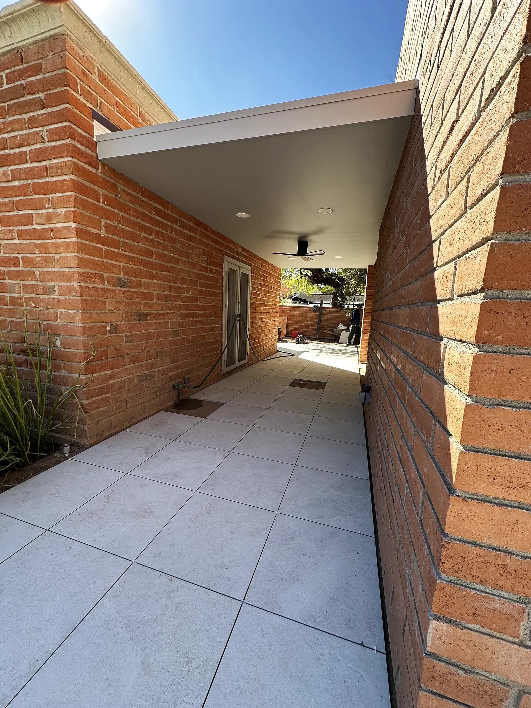 Large-format porcelain walkway running between original brick walls under a covered passage